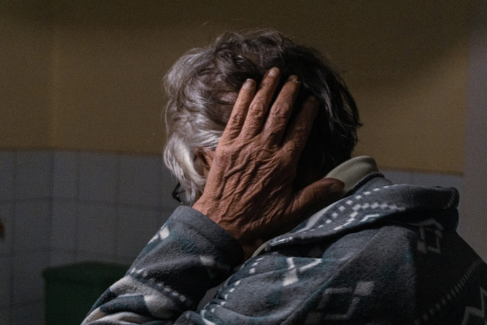 an older woman covering her face with her hands